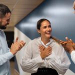 Woman expressing gratitude while coworkers clap for her.
