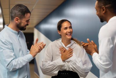 Woman expressing gratitude while coworkers clap for her.